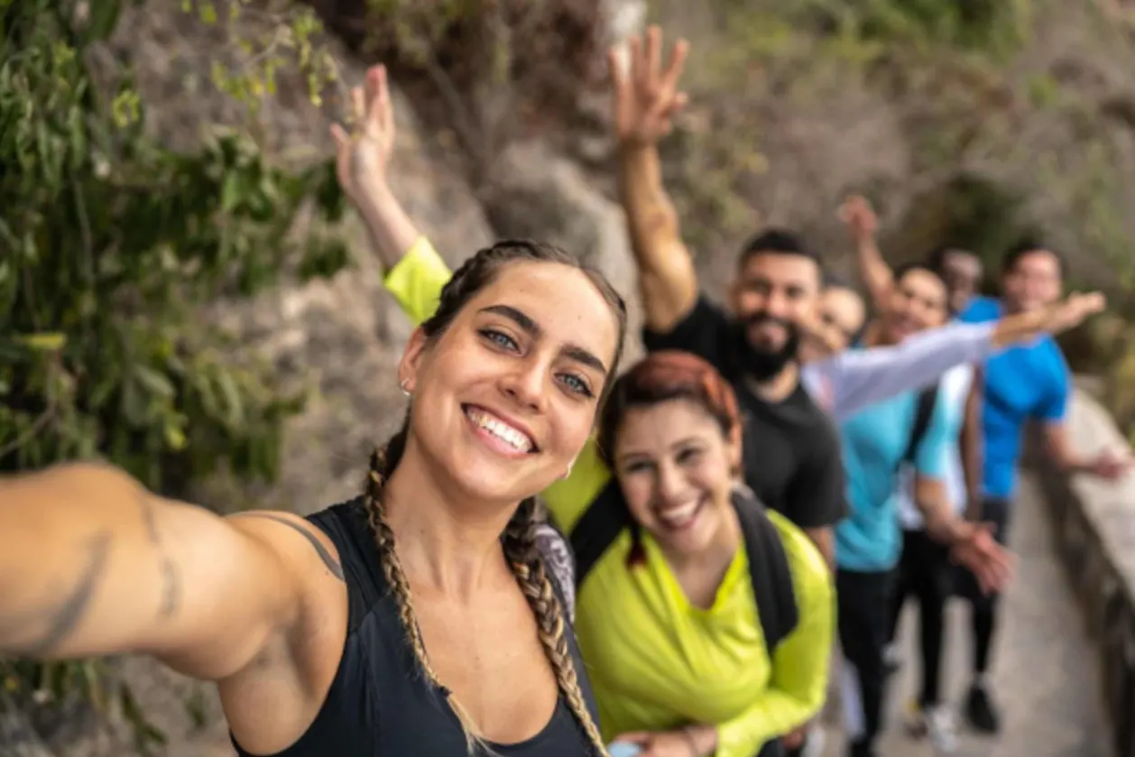 Woman taking a selfie with her friends during a fitcation hike outdoors